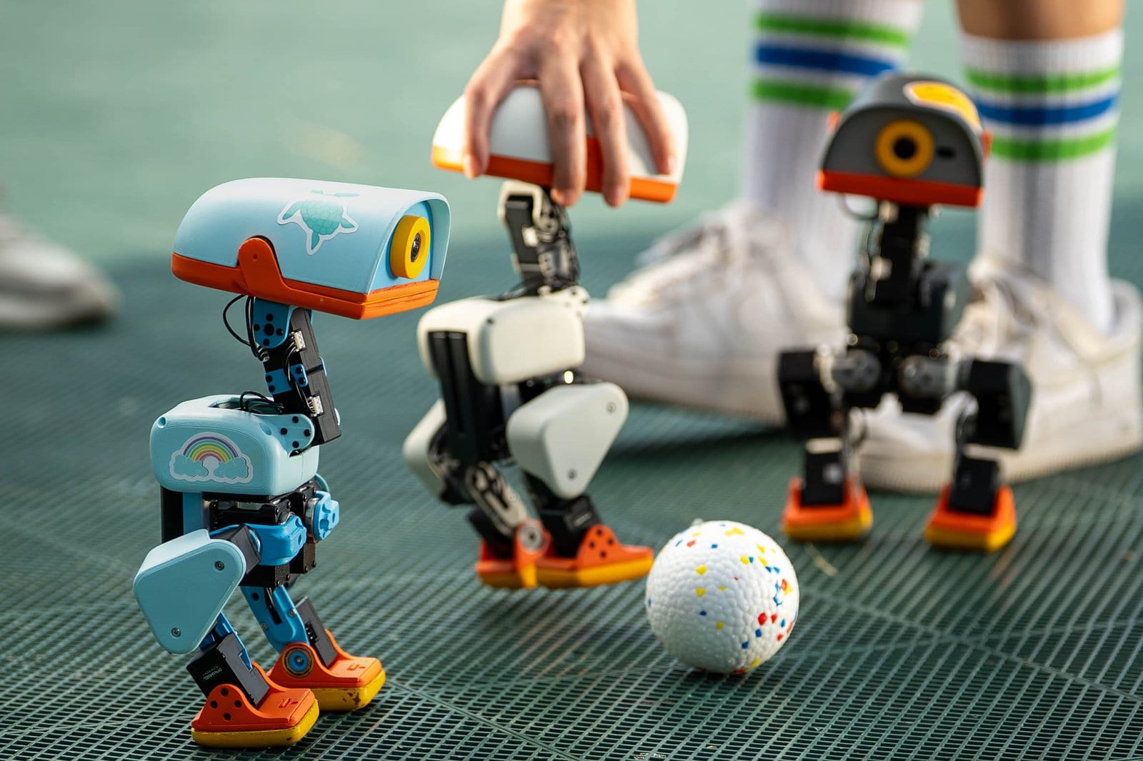 Weiße Roboter-Ente Microduck mit mechanischen Beinen auf Holzdielen in einer Wohnküche